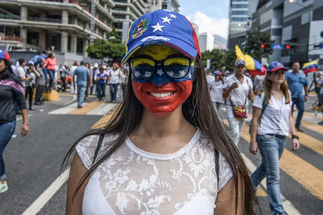 A woman seen smiling at the camera with her face painted in the venezuelan flag colors during a protest to call for a change in the government in Caracas, Venezuela on February 12, 2019. Opponents gather at a protest organised by the PSUV (United Socialist Party of Venezuela) after the call from interim president Juan Guaido, to show their support to him, while asking the army to allow more humanitarian aid into the country. (Photo by Roman Camacho/SOPA Images/Rex Features/Shutterstock)