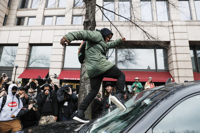 A protestor kicks in a windshield during a demonstration in Washington, Friday, January 20, 2017, after the inauguration of President Donald Trump. (Photo by John Minchillo/AP Photo)