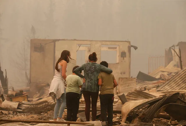 A woman and children look at the remains of a burnt house in Santa Olga, Chile, as the worst wildfires in Chile's modern history ravage wide swaths of the country's central-south regions, January 26, 2017. (Photo by Rodrigo Garrido/Reuters)