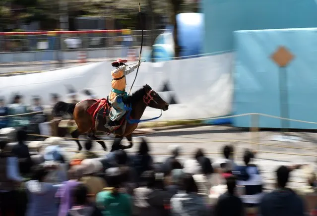 An archer wearing ancient samurai warrior dress shoots an arrow towards the target while riding on horseback during a Yabusame demonstration of the 13th-century samurai martial arts in Tokyo on April 18, 2015. (Photo by Toshifumi Kitamura/AFP Photo)