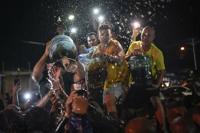 Devotees pour rum on to the statue of San Benito de Palermo, or Saint Benedict of Palermo, during a procession honoring the the patron Saint of Cabimas in Zulia state, Venezuela, Wednesday, December 27, 2023. (Photo by Matias Delacroix/AP Photo)
