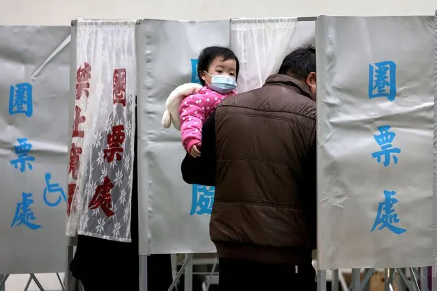 A man carries a child as he casts his ballot to vote in the presidential election at a polling station in a high school in Tainan on January 13, 2024. (Photo by Yasuyoshi Chiba/AFP Photo)