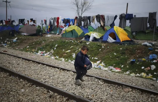 A migrant boy walks along railway tracks at a makeshift camp on the Greek-Macedonian border near the village of Idomeni, Greece March 10, 2016. (Photo by Stoyan Nenov/Reuters)