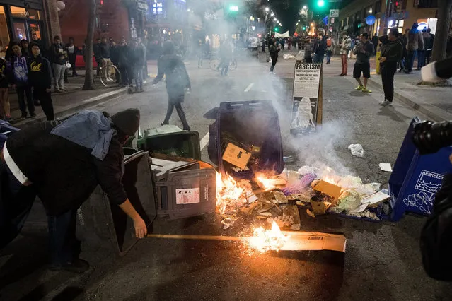 A demonstrator protesting Breitbart writer Milo Yiannopoulos sets a fire after a scheduled speech by Breitbart News editor Milo Yiannopoulos was cancelled, in Berkeley, California, USA, 01 February 2017. Hundreds of protesters rallied against Yiannopoulos, forcing the cancellation of his speech at UC Berkeley, eventually vandalizing dozens of businesses and smashing dozens of storefront windows. University police locked down all buildings after the protests turned violent. (Photo by Noah Berger/EPA)