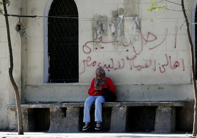 A woman sits in front of a wall with graffiti in support of the Ghalaba Movement, asking Egyptians to participate in demonstrations against the Egyptian regime on November 11, in Cairo, Egypt November 9, 2016. The words read, “Leave Sisi, Egypt not for sale”. (Photo by Amr Abdallah Dalsh/Reuters)