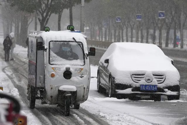 A delivery man moves past a car with a blanket of fresh snow in Beijing, China, Sunday, November 7, 2021. (Photo by Ng Han Guan/AP Photo)