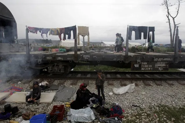 Refugees sit next to railway tracks in a makeshift camp for refugees and migrants at the Greek-Macedonian border near the village of Idomeni, Greece, March 23, 2016. (Photo by Alexandros Avramidis/Reuters)