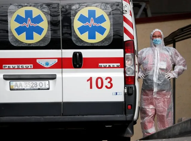 A health worker stands near an ambulance carring a COVID-19 patient, as they wait in the queue at a hospital for people infected with the coronavirus disease in Kyiv, Ukraine on October 18, 2021. (Photo by Gleb Garanich/Reuters)