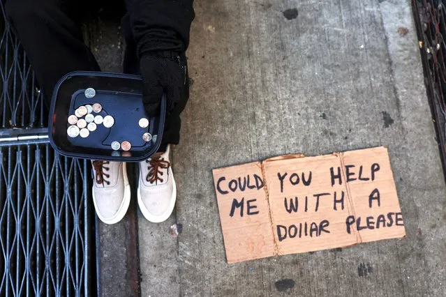 A man, 21, who said he was from Peru and has been homeless for around one year, shows a tray that he uses to collect spare change on a 44th street sidewalk in the Times Square area of New York City on March 12, 2024. (Photo by Shannon Stapleton/Reuters)