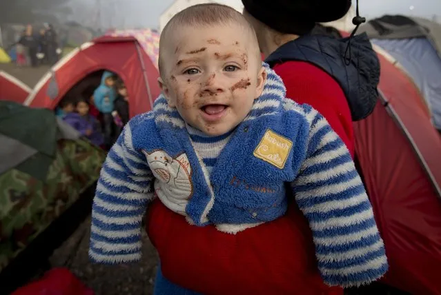 A child with chocolate stains on his face smiles in his mother's arm at the northern Greek border station of Idomeni, Friday, March 11, 2016. (Photo by Vadim Ghirda/AP Photo)