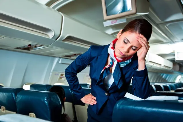 Young air stewardess suffering from headache on an airplane. (Photo by izusek/Getty Images)
