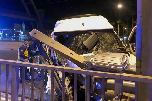 Turkish officials investigate after a minibus crashed near Aksu, in Antalya, Turkey, early Saturday, October 30, 2021. (Photo by IHA Agency via AP Photo)