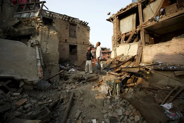 Men looks towards their collapsed house, a month after the April 25 earthquake in Kathmandu, Nepal May 25, 2015. (Photo by Navesh Chitrakar/Reuters)