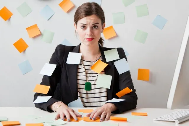 A woman sitting at a desk covered in post it notes. (Photo by Getty Images)