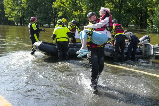 Conroe firefighter Cody Leroy carries a resident evacuated in a boat by the CFD Rapid Intervention Team from her flooded home in the aftermath of a severe storm, Thursday, May 2, 2024, in Conroe, Texas. (Photo by Brett Coomer/Houston Chronicle via AP Photo)