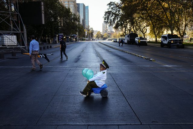 A child dressed as a police officer and accompanied by his parents, rides his toy vehicle to a demonstration seeking justice for police officers killed in the line of duty, in Santiago, Chile, Saturday, April 27, 2024. (Photo by Esteban Felix)/AP Photo)