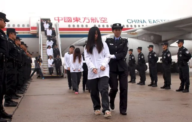 Suspects involved in telecom fraud walk off a plane after being repatriated from overseas, at an airport in Beijing, China, November 10, 2015. (Photo by Reuters/China Daily)