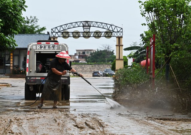 A worker clears mud from a road after torrential rains flooded the area in Qingyuan, in northern Guangdong province on April 24, 2024. More than 100,000 people have been evacuated due to heavy rain and fatal floods in southern China, with the government issuing its highest-level rainstorm warning for the affected area. (Photo by Hector Retamal/AFP Photo)