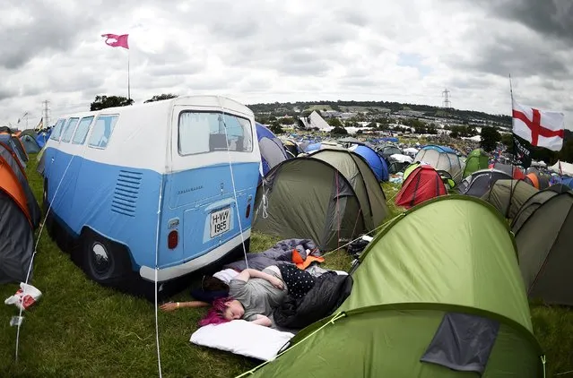 Revellers sleep beside a camper van style tent during the Glastonbury Festival at Worthy Farm in Somerset, Britain, June 25, 2015. (Photo by Dylan Martinez/Reuters)