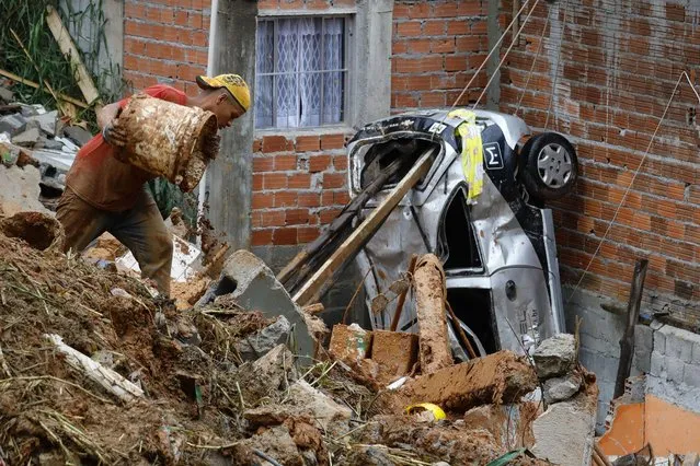 A volunteer searches for people in the rubble after heavy rain triggered a landslide in Franco da Rocha, Sao Paulo state, Brazil, Monday, January 31, 2022. Landslides and flooding caused by heavy rains have killed over a dozen people and forced about 500,000 families from their homes, authorities said. (Photo by Marcelo Chello/AP Photo)
