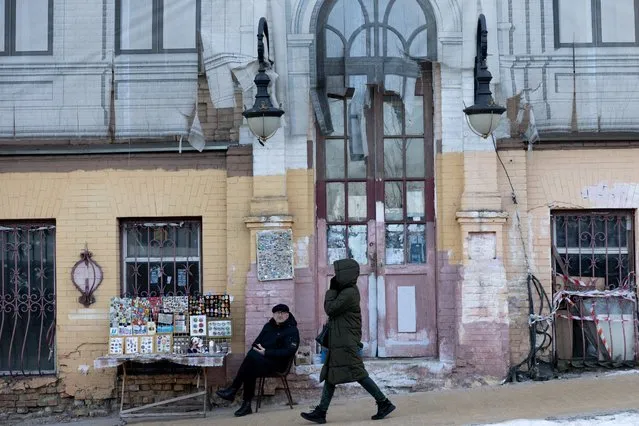 A woman walks past a man selling vintage items on the street on February 15, 2022 in Kyiv, Ukraine. (Photo by Chris McGrath/Getty Images)