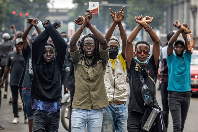 Protesters make signs with their arms in front of Kenya police officers during a demonstration against tax hikes as Members of the Parliament debate the Finance Bill 2024 in downtown Nairobi, on June 18, 2024. Kenyan police fired tear gas and arrested dozens of demonstrators on June 18, 2024 as hundreds of people gathered near the Parliament building to protest tax hikes. (Photo by Luis Tato/AFP Photo)