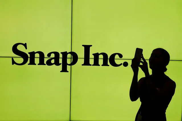 A woman stands in front of the logo of Snap Inc. on the floor of the New York Stock Exchange (NYSE) while waiting for Snap Inc. to post their IPO, in New York City, NY, U.S. March 2, 2017. (Photo by Lucas Jackson/Reuters)