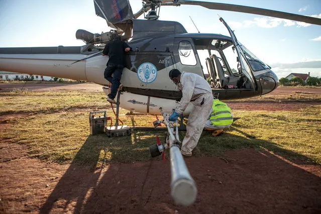 Men prepare a helicopter of the Food and Agriculture Organization of the United Nations (FAO), equipped with pesticide spreading equipment to fight a swarm of locusts, before taking off on May 7, 2014 in Tsiroanomandidy, Madagascar. (Photo by AFP Photo/RIJASOLO)