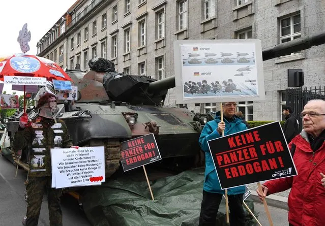 Demonstrators hold posters reading “No tanks for Erdogan!” as they protest with a Leopard tank taken out of service on May 9, 2017 in front of Berlin's Maritim hotel, venue of the annual general meeting of German arms company Rheinmetall. (Photo by Bernd Settnik/AFP Photo/DPA)