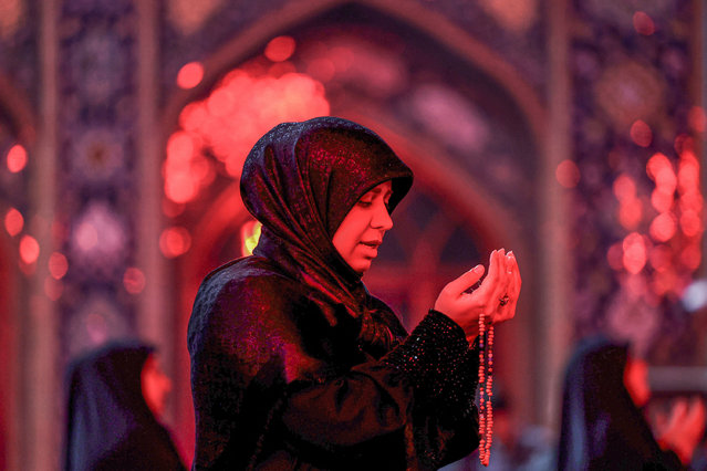 A woman prays during a gathering with other devotees for the ritual prayers for Laylat al-Qadr (Night of Destiny), one of the holiest nights during the Muslim fasting month of Ramadan, outside the Imamzadeh Saleh mosque in Tehran, on April 10, 2023. (Photo by Atta Kenare/AFP Photo)