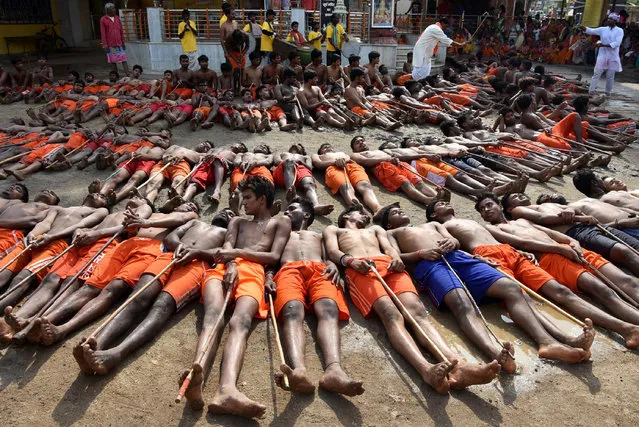 Indian farmers lie with sticks outside Shiva Temple in Ranchi on May 10, 2017, as they wait for blessings from the main priest of the temple during the “Manda” Festival. Many tribal farmers take part in the ritual as they believe the Hindu God Shiva will bestow upon them good crops and health leading to prosperity. (Photo by AFP Photo/Stringer)