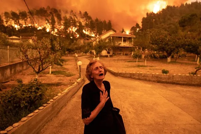An elderly resident reacts as a wildfire approaches her house in the village of Gouves, on the island of Evia, Greece, on Sunday, August 8, 2021. Thousands of residents were evacuated from the Greek island of Evia by boat after wildfires hit Greeces second biggest island. (Photo by Konstantinos Tsakalidis/Bloomberg via Getty Images)