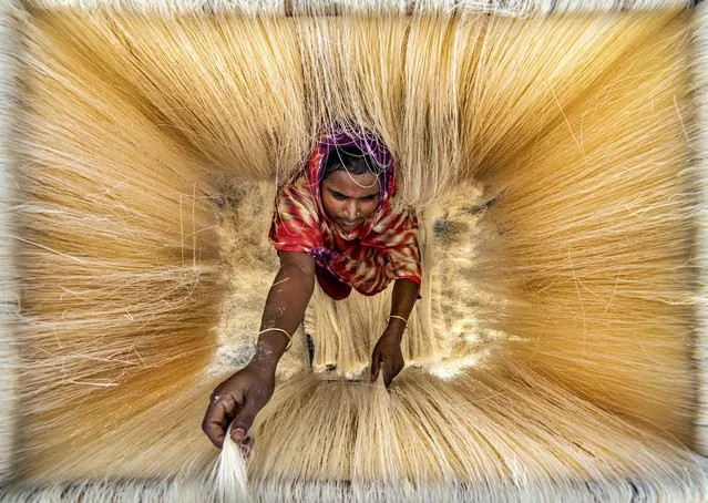 Millions of noodles hang like strands of hair as a worker arranges them to dry in the sun in Bogura, Bangladesh on April 14, 2022. (Photo by Abdul Momin/Solent News)