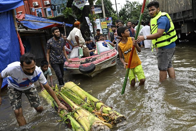 Volunteers use a boat to help rescue people on a flooded street following heavy rains in Mohipal, Feni, a coastal district in southeast Bangladesh, Friday, August 23, 2024. (Photo by Fatima Tuj Johora/AP Photo)