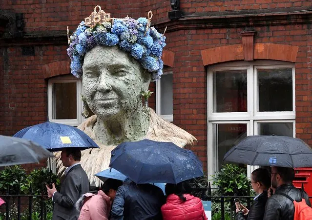 People shield from the rain as they walk past a floral representation of Britain's Queen Elizabeth, which forms part of the Chelsea In Bloom festival running at the same time as Chelsea Flower Show in London, Britain, May 24, 2022. (Photo by Toby Melville/Reuters)
