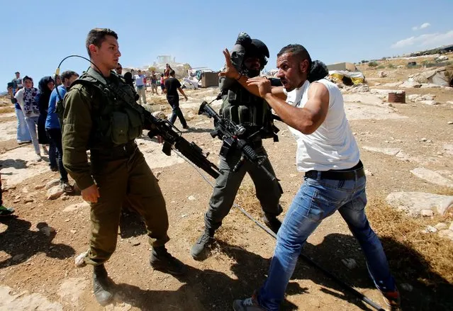 An Israeli border policeman detains a Palestinian man as Israeli troops demolish sheds belonging to Palestinians near the West Bank village of Yatta, south of Hebron June 19, 2016. (Photo by Mussa Qawasma/Reuters)