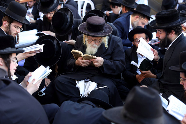 Orthodox Jews pray as they read from the book of Eicha (Book of Lamentations) to mark Tisha B'av, at The Western Wall, in the Old City of Jerusalem on July 27, 2023. In Judaism, the Tisha B'Av is an annual fast day to mark the destruction of the first and the second temple by the Babylonian and the Roman Empires in Jerusalem. During Tisha B'av, Ultra-Orthodox Jews stay up all night and sleep at the Western Wall as they recite lamentations focusing on the destruction of the ancient temple, that was located on the other side of the ancient wall, on the Temple Mount. (Photo by Abir Sultan/EPA/EFE)