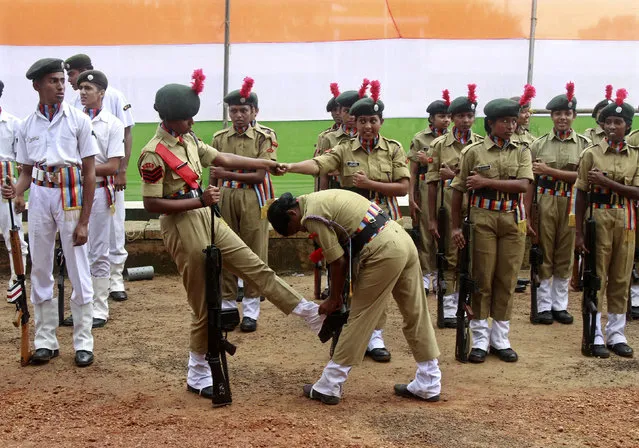 A female cadet helps her comrade fix her boots before the start of the Independence Day parade in India. (Photo by Sivaram V/Reuters)