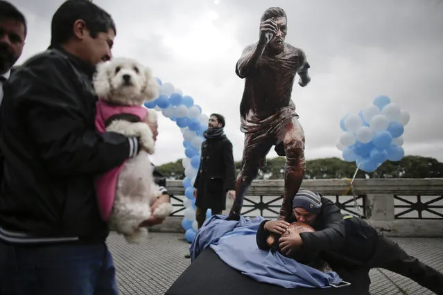 A man kisses a statue of soccer star Lionel Messi shortly after it was unveiled in Buenos Aires, Argentina, Tuesday, June 28, 2016. Fans, players, and even Argentina's President Mauricio Macri and the country's greatest player Diego Maradona have asked Messi to reconsider his decision to resign from the national team after losing the Copa America final to Chile. (Photo by Victor R. Caivano/AP Photo)