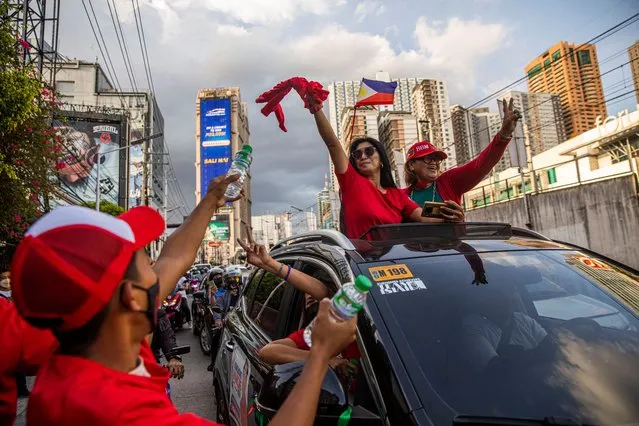 Supporters of Ferdinand “Bongbong” Marcos Jr. hold up two fingers in a show up support while driving past his headquarters as partial results roll in and show him in the lead on May 10, 2022 in Manila, Philippines. Ferdinand “Bongbong” Marcos Jr. is poised to win the presidency in a hotly contested election marred by several incidents of violence and numerous complaints of faulty vote counting machines. Marcos, the son and namesake of ousted dictator Ferdinand Marcos Sr. who was accused and charged of amassing billions of dollars of ill-gotten wealth as well as committing tens of thousands of human rights abuses during his autocratic rule, mounted a hugely popular campaign based largely on disinformation to return his family name to power. Election results a day after millions of Filipinos went to polls show Marcos enjoying a massive lead against main rival Vice President Leni Robredo. Also poised to win the vice presidency is Mayor Sara Duterte of Davao City, the daughter of outgoing President Rodrigo Duterte who is the subject of an international investigation for alleged human rights violations during his war on drugs. (Photo by Lauren DeCicca/Getty Images)