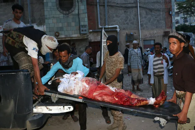 Tribal fighters, against Shiite rebels known as Houthis, carry the body of a man who was killed during fighting between the two groups, in Taiz, Yemen, Tuesday, Aug. 20, 2015. In Taiz, Yemen's third largest city, at least 11 civilians were killed and more than 35 injured by shelling that started on Wednesday, independent local officials, witnesses and medical officials said, speaking on condition of anonymity because they were not authorized to talk to reporters. (Photo by Abdulnasser Alseddik/AP Photo)