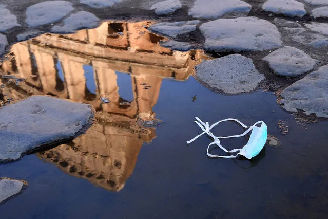 The Colosseum, that will be closed following the government's new prevention measures on public gatherings, is reflected in a puddle where a face mask was left, in Rome, Sunday, March 8, 2020. Italy announced a sweeping quarantine early Sunday for its northern regions, igniting travel chaos as it restricted the movements of a quarter of its population in a bid to halt the new coronavirus' relentless march across Europe. (Photo by Alfredo Falcone/LaPresse via AP Photo)