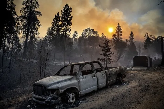 The Oak Fire burns behind a scorched pickup truck in the Jerseydale community of Mariposa County, Calif., early Sunday, July 24, 2022. (Photo by Noah Berger/AP Photo)