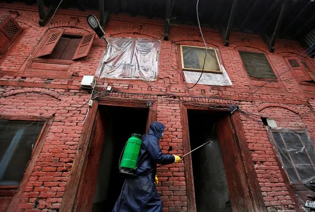 A municipal worker wearing a protective suit disinfects the premises of a police station as a preventive measure against the spread of coronavirus disease (COVID-19), in Srinagar on March 30, 2020. (Photo by Danish Ismail/Reuters)