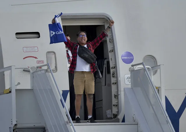 A passengers from the British cruise ship MS Braemar cheers from the plane's door before being flown to the UK, at the José Martí International Airport in Havana, Cuba, Wednesday, March 18, 2020. Cuba authorized on Wednesday the British cruise ship MS Braemar, with five confirmed cases of the new coronavirus and more than 1000 people on board, to dock on the island, from where its passengers will be repatriated by plane. (Photo by Yamil Lage/Pool Photo via AP Photo)