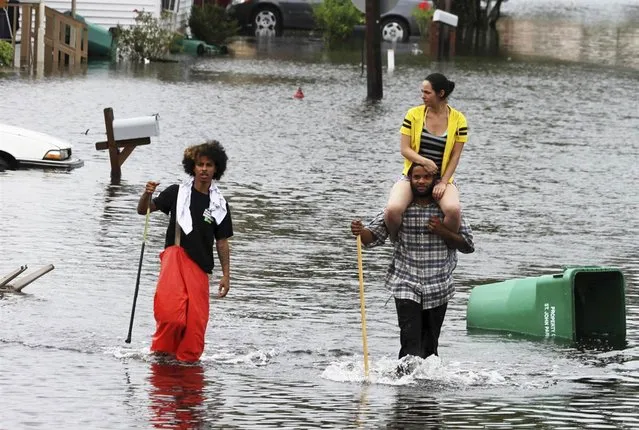 Joseph Egana carries his fiancee Felicia Brewer as they wade, along with Derreck Eugene, through flooded Pine Street in LaPlace, La., on Aug. 30. (Photo by Peter Forest/Reuters)