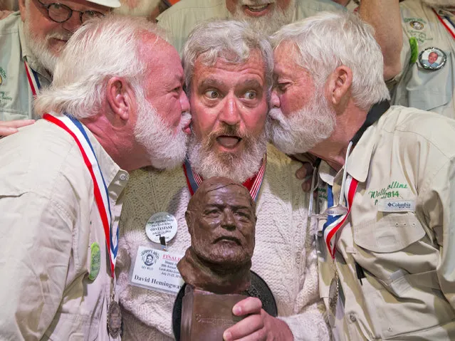 In this Saturday, July 23, 2016 photo provided by the Florida Keys News Bureau, Dave Hemingway, center,  receives smooches from Charlie Boise, left, and Wally Collins, right, after Hemingway won the 2016 Ernest “Papa” Hemingway Look-Alike Contest in Key West, Fla. Success for Dave Hemingway came on the Macon, N.C., resident's seventh attempt to win the coveted title at Sloppy Joe's Bar. Dave Hemingway is not related to Ernest Hemingway who lived and wrote in Key West in the 1930s. (Photo by Rob O'Neal/Florida Keys News Bureau via AP Photo)