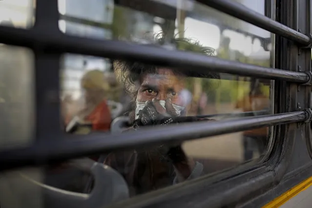 An Indian homeless man sits in a bus as he is being evicted with other homeless people and migrant laborers from the banks of Yamuna River where they have been squatting during lockdown in New Delhi, India, Wednesday, April 15, 2020. Indian Prime Minister Narendra Modi on Tuesday extended the world's largest coronavirus lockdown to head off the epidemic's peak, with officials racing to make up for lost time. (Photo by Altaf Qadri/AP Photo)