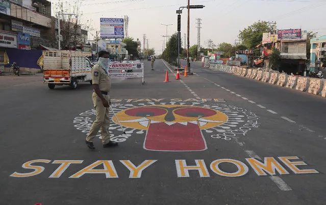An Indian policeman walks past an art work displayed on road urging people to stay home during lockdown to prevent the spread of new coronavirus in Hyderabad, India, Wednesday, April 22, 2020. India has reported nearly 20,000 confirmed cases of COVID-19 and over 600 deaths. (Photo by Mahesh Kumar A./AP Photo)
