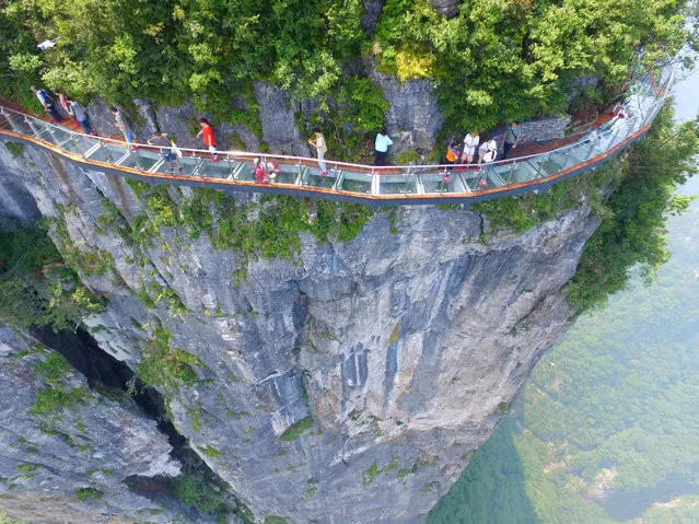 Aerial view of tourists walking on the 100-meter-long and 1.6-meter-wide glass skywalk clung the cliff of Tianmen Mountain (or Tianmenshan Mountain) in Zhangjiajie National Forest Park on August 1, 2016 in Zhangjiajie, Hunan Province of China. (Photo by  Imaginechina/Rex Features/Shutterstock)